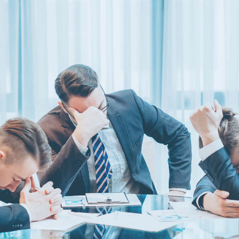 professional men at table looking frustrated